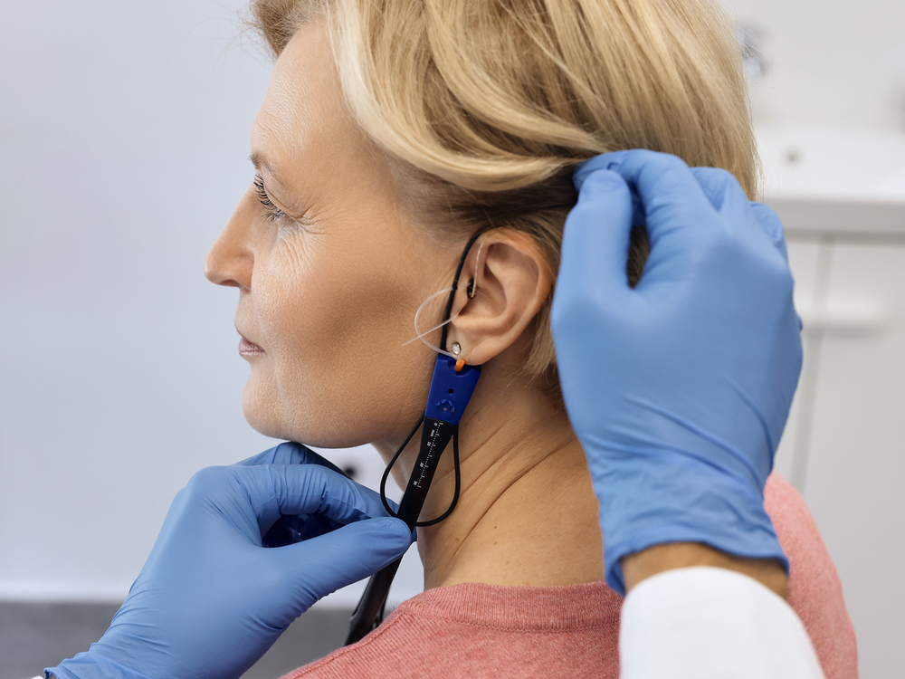 Doctor of Audiology performing real ear measurement on a hearing aid patient at Advanced Hearing Technology in Naples, FL
